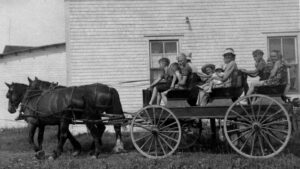 This is an old black and white photo of MacLaren Redfern family going for a ride on horse and cart. There are lots of children and a few adults.